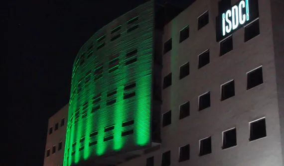 Clădire de birouri cu fațada scăldată în lumină verde, noaptea